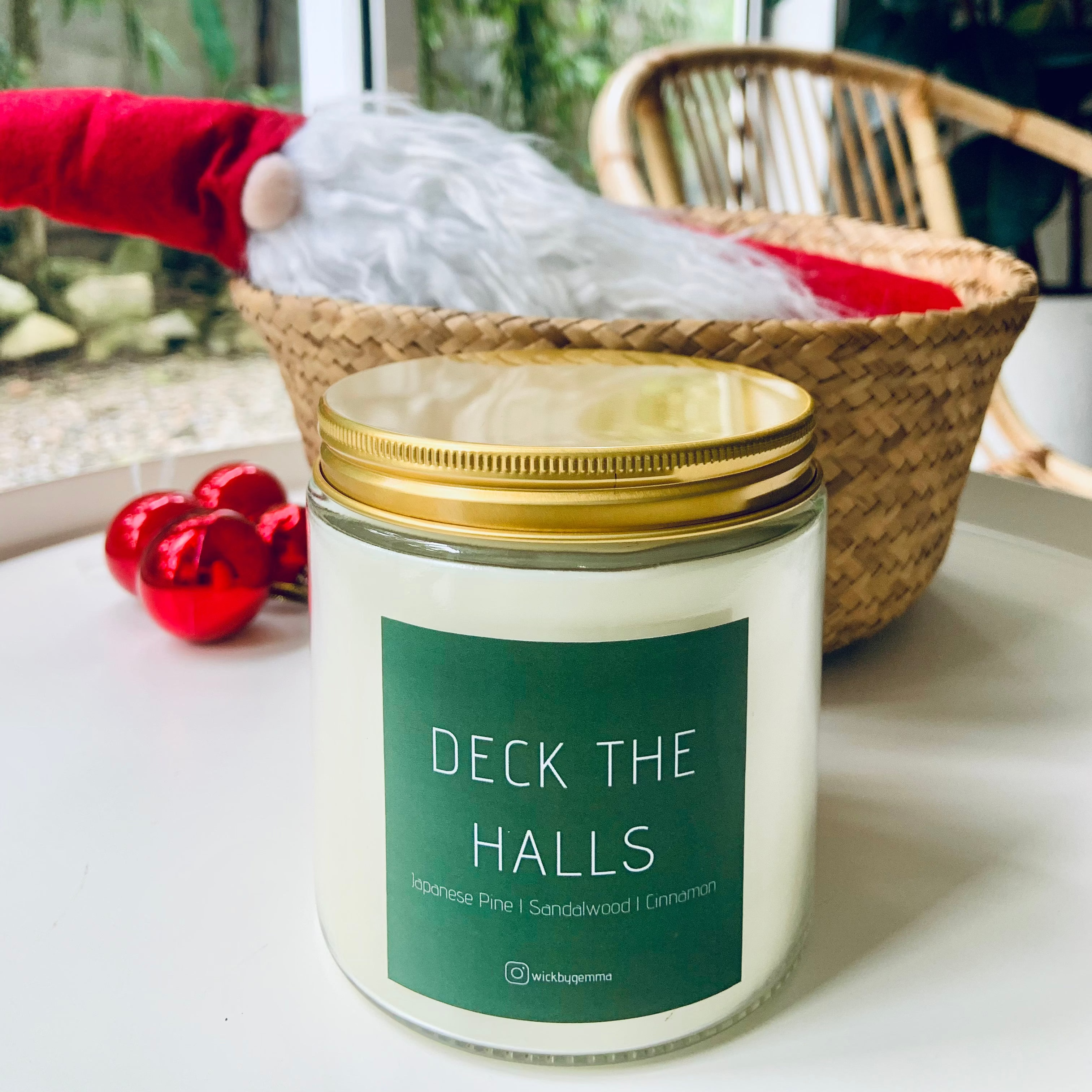 Candle labeled 'Deck the Halls' on a surface with a festive background