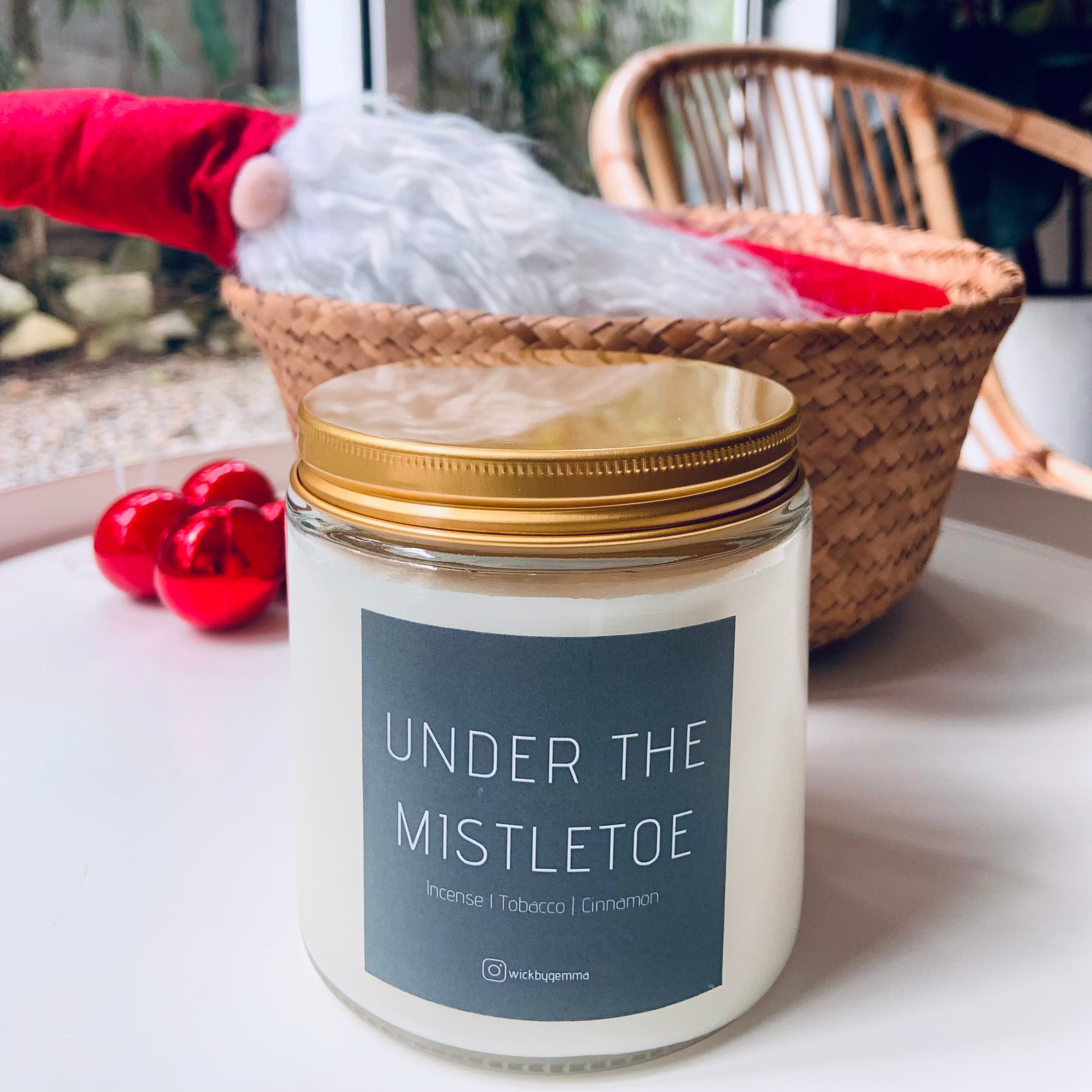 Candle labeled 'Under the Mistletoe' on a table with a festive background